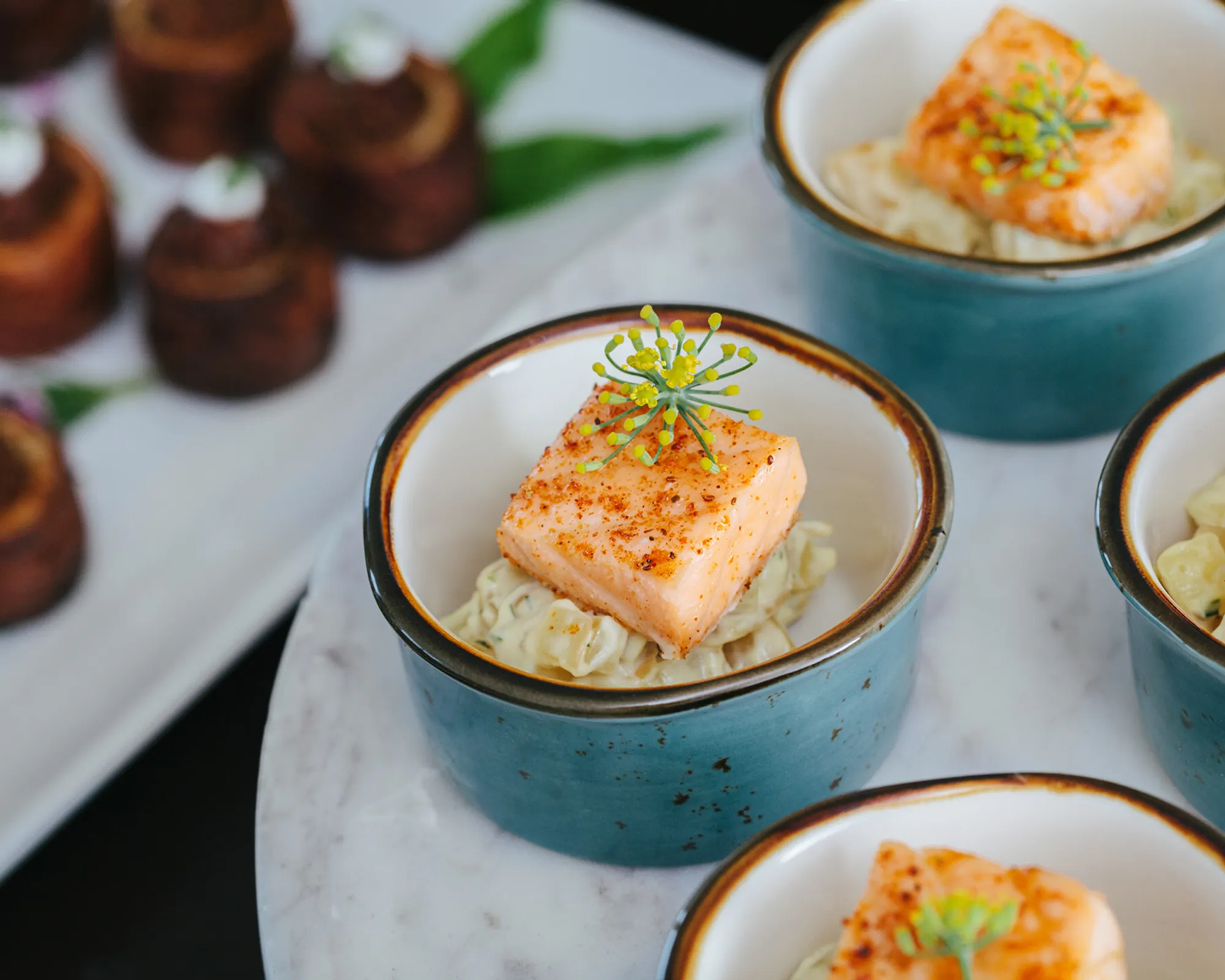 Salmon and grains in blue bowls atop a marble tabletop