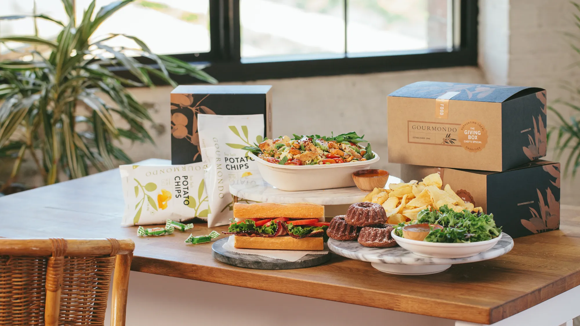 A wooden table with plates of food and packaging